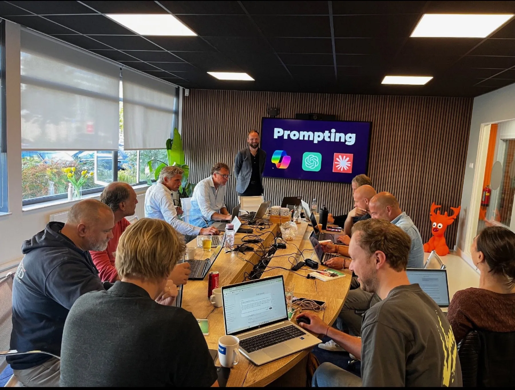 Deelnemers met hun laptop rond één tafel op het NinA AI kantoor